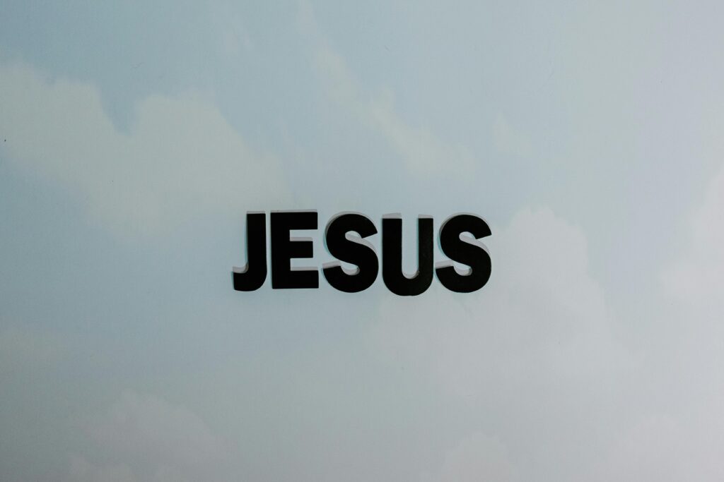 Minimalist image with bold 'JESUS' text against a cloudy sky background.